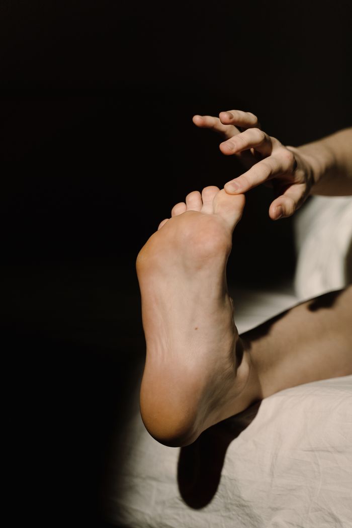 Minimalist image of a foot and hand in soft light, highlighting skin texture and form.